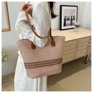 Side view of a large woven tote bag with brown leather straps shown on a model