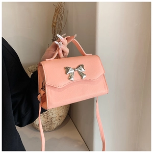 Detail of coral pink crossbody bag with cross-grain texture and silver bow buckle