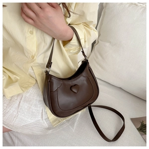 Detail of dark brown heart-embossed crossbody bag with smooth faux leather texture