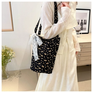 Floral shoulder tote bag with lace bow accessory shown in a cozy lifestyle setting