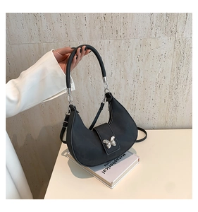 Détail d'un sac hobo noir avec boucle papillon argentée et finition nylon brillant