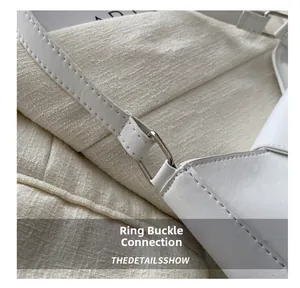 Close-up of white leather handbag showing silver buckle and detailed stitching