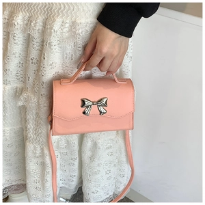 Detail of pink faux leather bag with silver metal bow and sturdy top handle