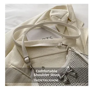 Detail of white rhinestone shoulder bag featuring a silver bow and adjustable strap