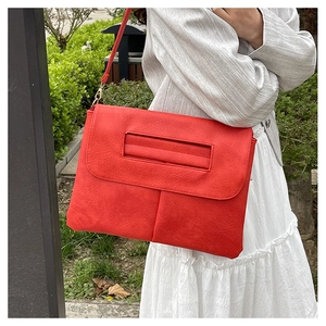 Détail du grand sac enveloppe rouge en cuir PU texturé avec des boucles en métal doré