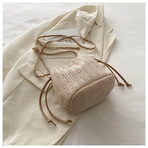Detailed view of beige woven bucket bag with herringbone texture and chain strap