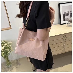 Dettaglio borsa tote in nylon rosa chiaro con catena dorata e logo di alta moda