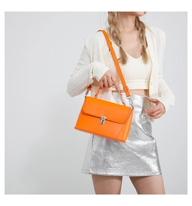 Detail of bright orange crossbody bag featuring silver metallic twist lock and leather strap