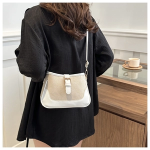Detail of minimalist beige canvas crossbody bag with white leather trim and gold buckle