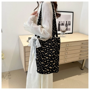 Detail of black floral tote bag with yellow flowers and a white lace bow decoration