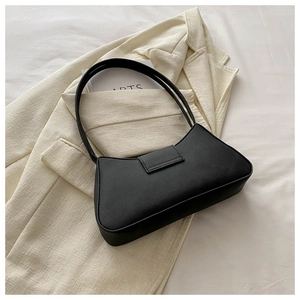 Detail of minimalist black baguette bag with slim strap on a stylish blazer background