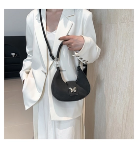 Détail du sac croissant avec boucle papillon argentée sur une tenue de tailleur blanc