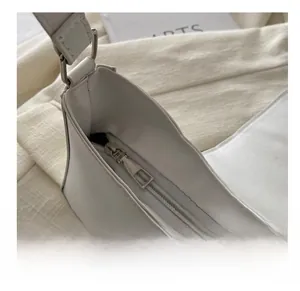 Close-up of smooth metal zipper and premium white leather texture on underarm bag