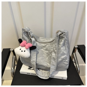 Détail d'un sac cabas argenté plissé avec breloque peluche sur une chaise chic