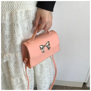 Detailed view of pink crossbody bag featuring a silver bow and lychee grain leather