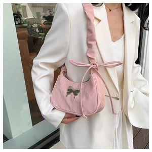 Detail of pink pleated underarm bag featuring a metallic butterfly ornament and ruffled strap
