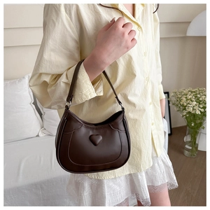 Detail shot of brown crescent leather bag featuring a 3D heart motif and shoulder strap