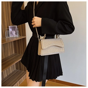 Close-up of golden glitter crossbody bag with curved flap and elegant metallic finish