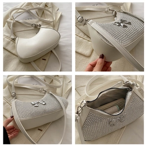 Detail view of white crescent bag showing silver studs, bow detail, and interior storage