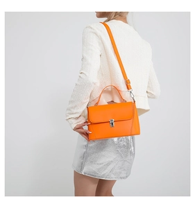 Detail of bright orange square handbag with silver clasp on white knit sweater