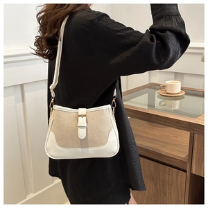 Modern woven crossbody bag with cream leather trim shown on shoulder in stylish setting