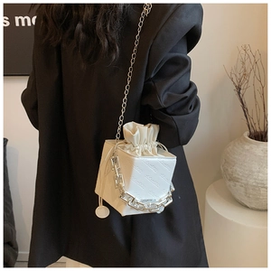 Detail of white box bag with embossed letters, silver chain strap, and drawstring closure