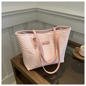 Detail of pink quilted tote bag with wavy stitching and narrow shoulder straps