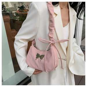 Close-up of pink satin shoulder bag with metallic butterfly charm and pleated strap