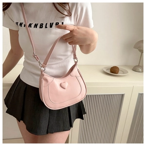 Detail of light pink half-moon bag featuring a 3D heart design and silver metal buckle