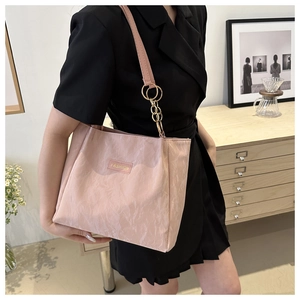 Dettaglio borsa tote rosa a pieghe con catena dorata e logo moda indossata da modella