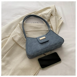 Detailed macro of dark blue baguette bag with gold buckle and textured fabric finish