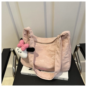 Détail du sac cabas plissé rose avec un pendentif chien en peluche sur une chaise