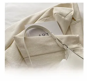 Close-up of cream white underarm bag side details with silver bow and slim strap