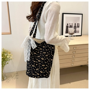 Close-up of black floral tote bag featuring a prominent white lace bow detail