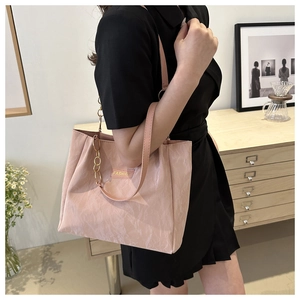 Dettaglio borsa tote rosa pieghettata con catena dorata e etichetta moda su modella