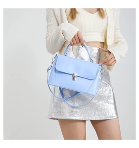 Detail of light blue crossbody bag with silver metal buckle on a fashion model outfit