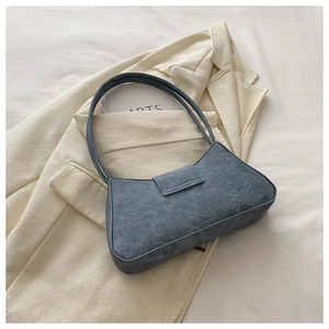 Close-up of retro gray-blue baguette bag with denim texture on a blazer