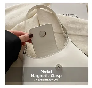 Close-up of the silver magnetic closure on a white faux leather crossbody bag