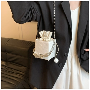 Detail of white square bucket bag with embossed lettering and thick silver chain strap