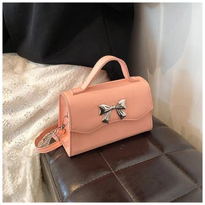 Detailed shot of a pink crossbody bag with silver bow buckle on leather seat