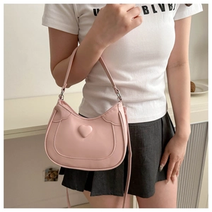 Detail of pink half-moon shoulder bag featuring a 3D heart design and PU matte finish