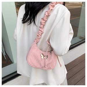 Detailed view of pink textured fabric bag with golden butterfly logo and ruffled strap