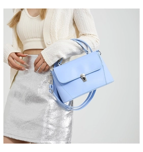 Detail of light blue vintage square bag with silver clasp held by model in stylish outfit