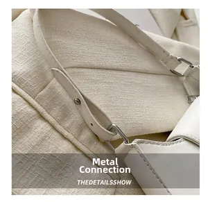 Detailed close-up of the polished silver metal hardware on a white leather handbag