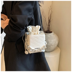 Detail of white drawstring bucket bag with rich rabbit texture and silver chain strap