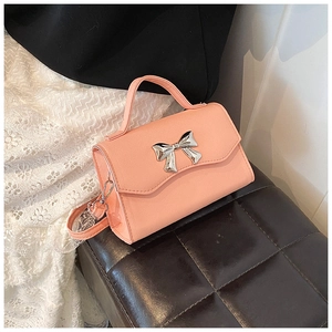 Detail of pink crossbody bag with silver metal bow and textured synthetic leather