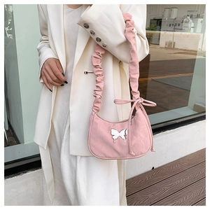 Detail view of pink hobo bag with scrunchie handle and silver butterfly charm on beige blazer