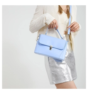 Detail of light blue PU leather handbag with silver buckle and thin shoulder strap