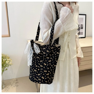 Close-up of black floral canvas tote bag featuring white lace ribbon detailing
