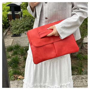 Gros plan sur une grande pochette enveloppe rouge avec texture cuir et dragonne femme